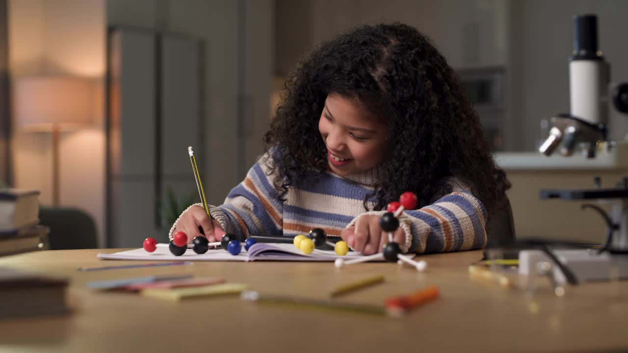 一个小女孩独自坐在家里用放大镜做科学作业的4k视频片段视频素材