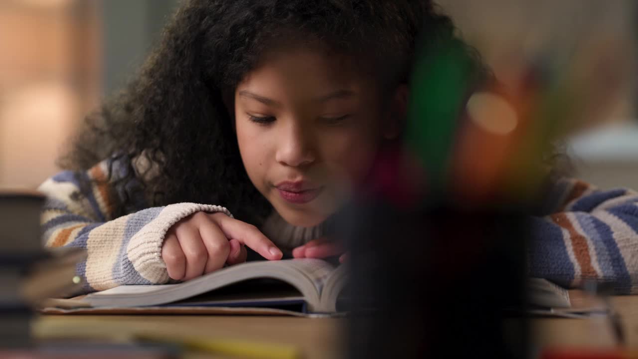 一个小女孩独自坐在家里读课本的4k视频片段视频素材