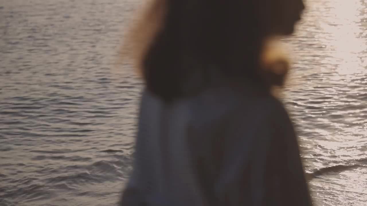 快乐的年轻女子走到海边美丽的落日剪影视频素材