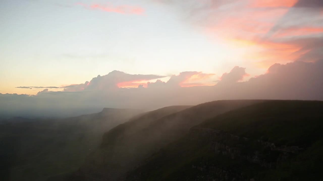 自然景观:在日落或黎明的背景下，云朵越过山丘和山脉视频素材