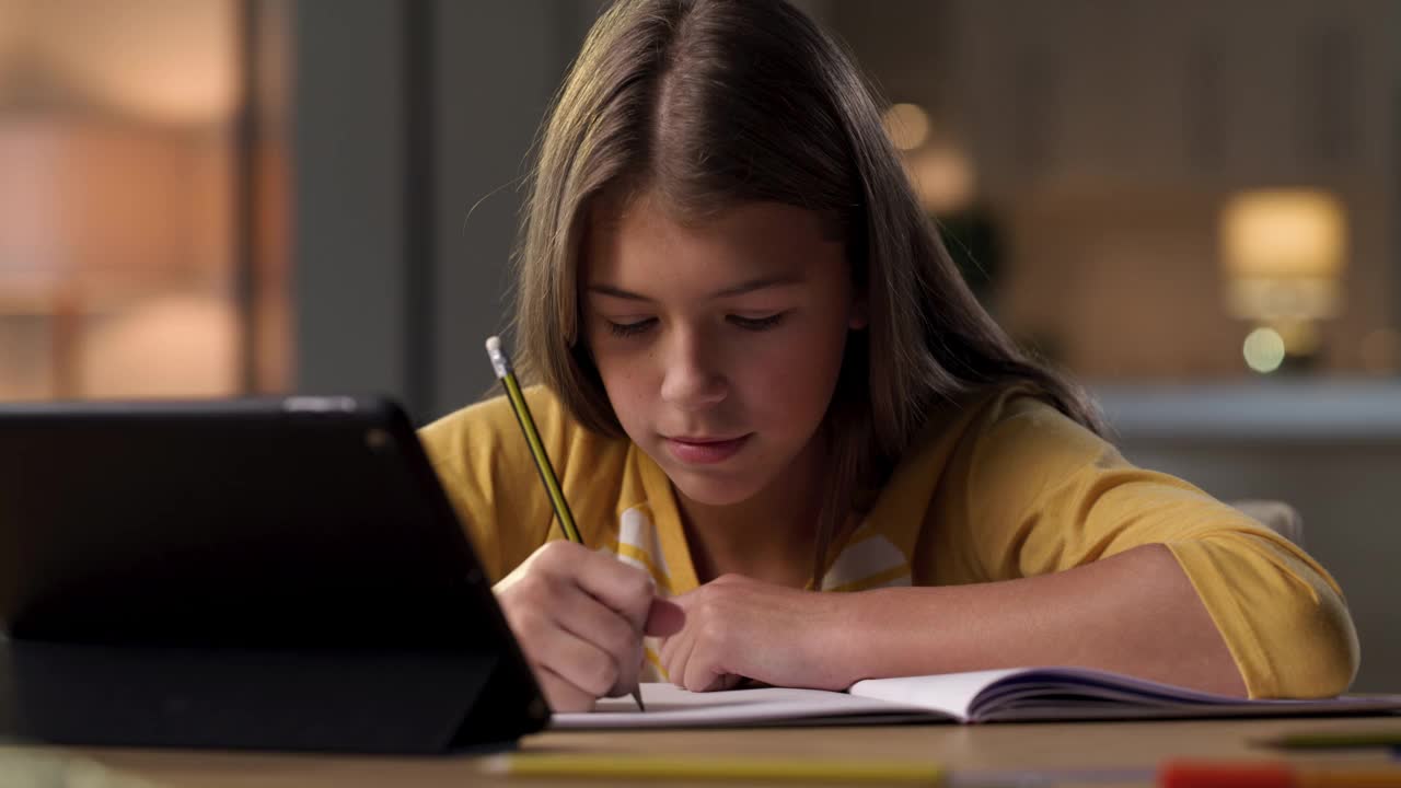 一个小女孩独自坐在家里用平板电脑上虚拟课堂的4k视频片段视频素材