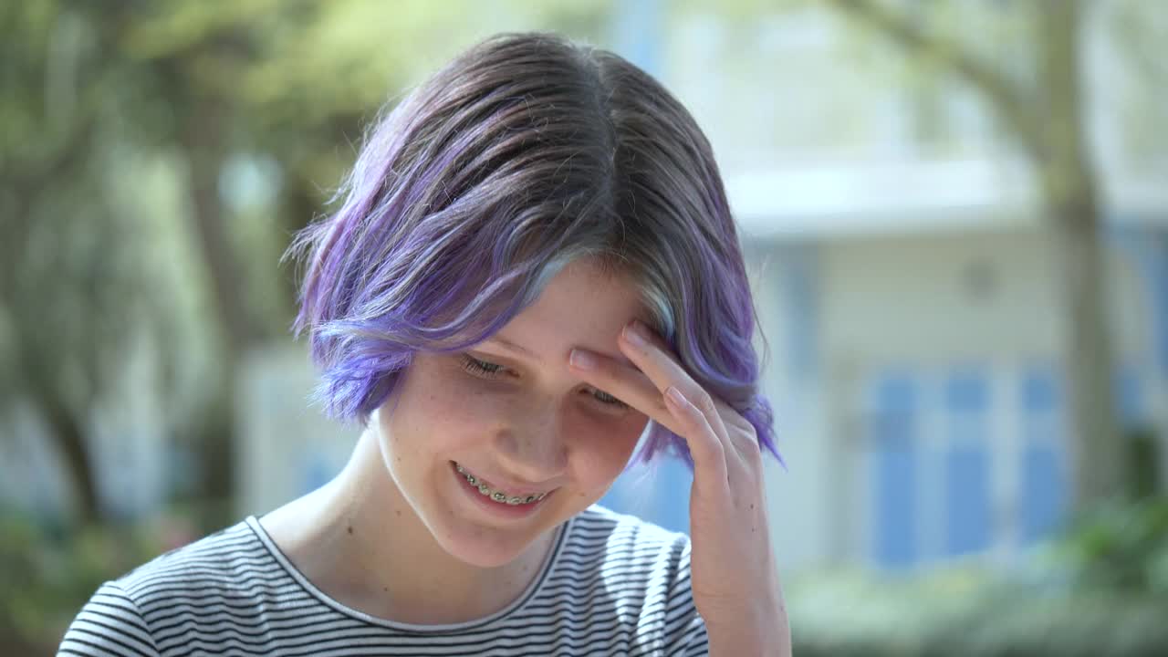 一个紫色头发戴着牙套的少女摇着头视频下载