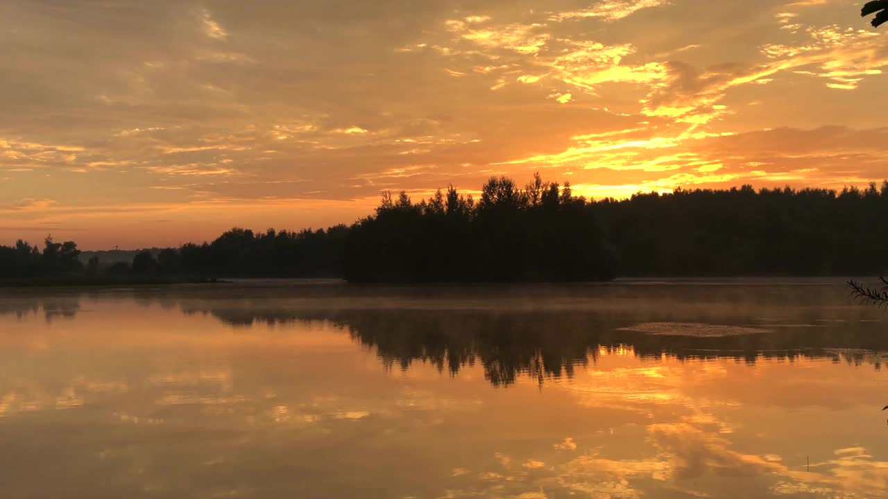 湖上的夕阳天空，地平线上森林的轮廓视频素材