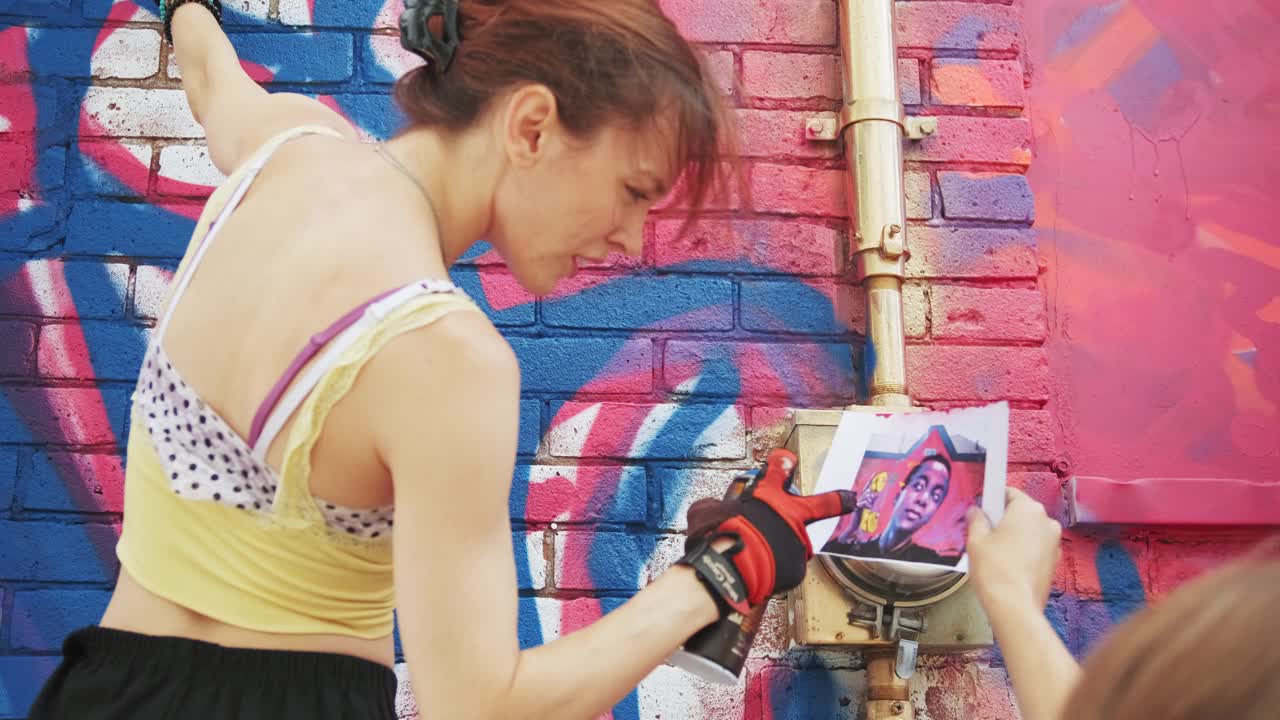 年轻女子在房子上画壁画视频素材