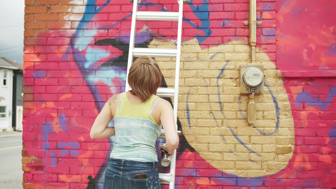 年轻女子在房子上画壁画视频素材