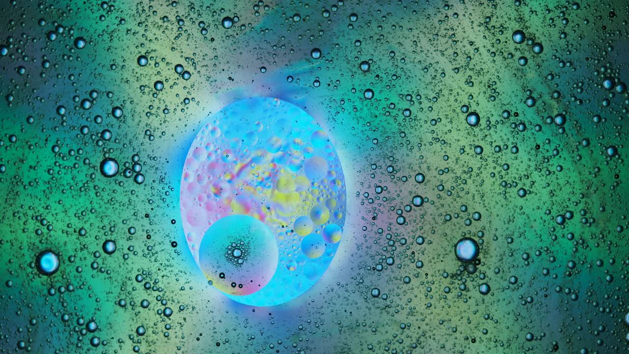 行星形状的液体气泡，漂浮在五颜六色的液体表面。视频素材