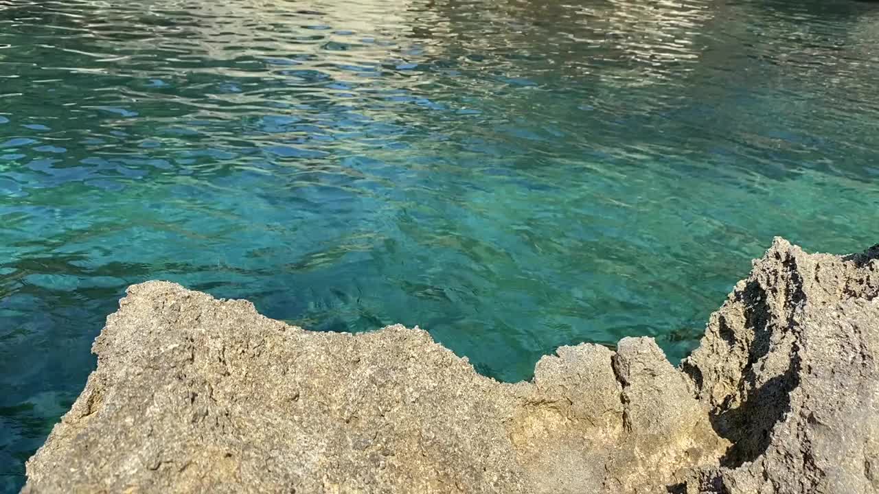 蓝绿色的海水和海岸岩石。清澈的地中海。美丽晶莹的绿蓝色水彩画。蓝色泻湖的海岸悬崖。视频素材