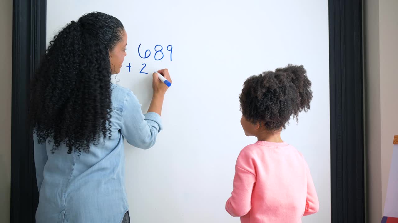 母亲在家教女儿，在白板上做数学视频素材