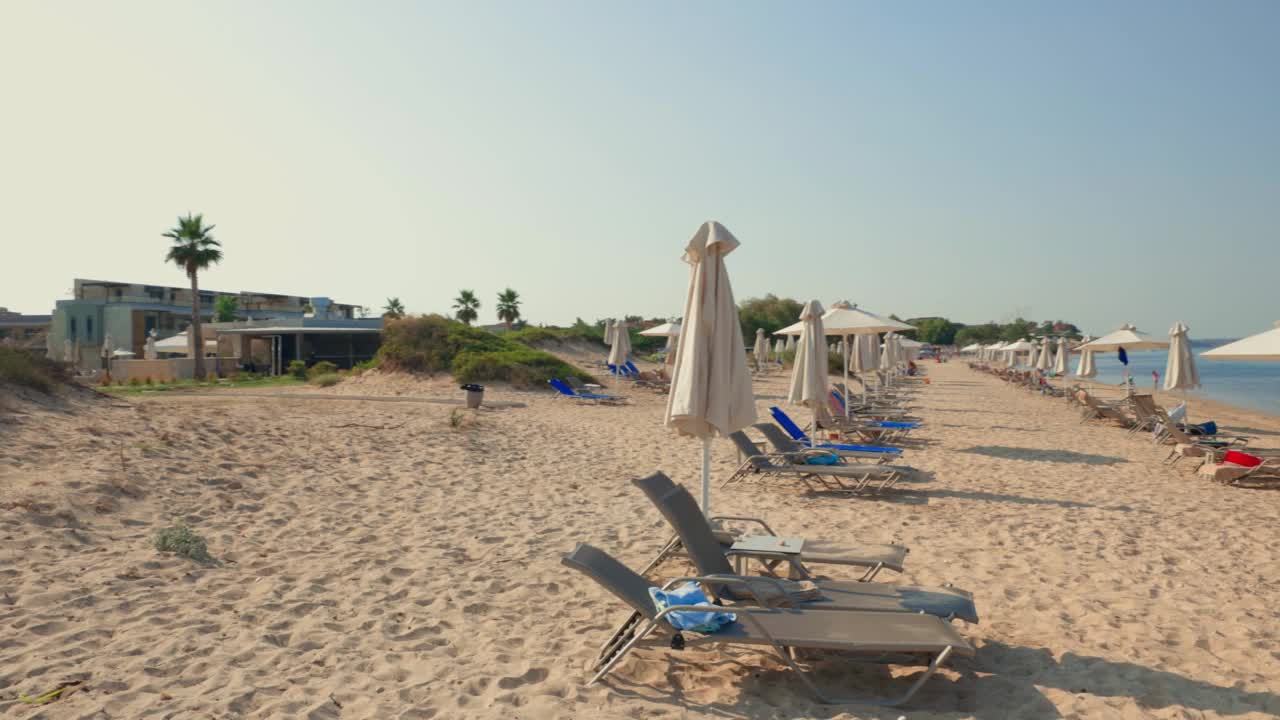 阳光明媚的夏日，沙滩上空荡荡的日光浴床的美丽景色。希腊。视频素材