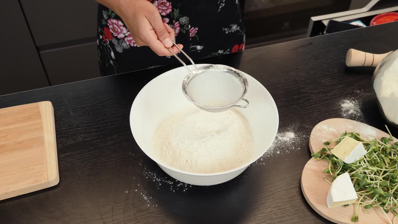 在准备做披萨的生面团时，用筛子筛面粉。妇女用筛子筛面粉，为家人做传统的意大利披萨。烹饪过程视频下载