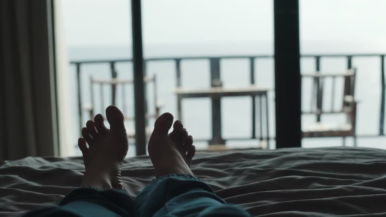放松的人们躺在床上，交叉腿在毯子上，在酒店度假胜地看风景视频下载