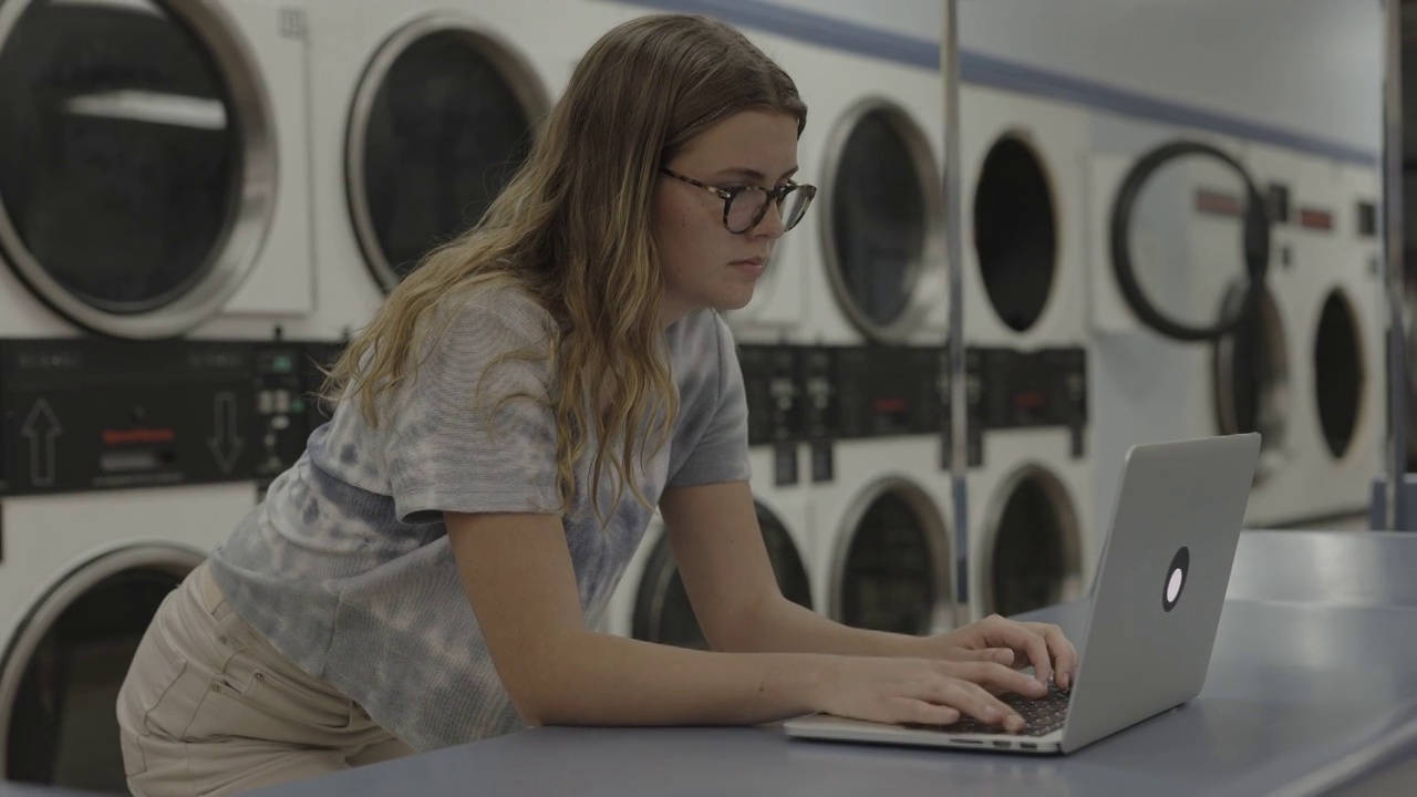 美国犹他州普罗沃洗衣店的女孩在使用笔记本电脑视频素材
