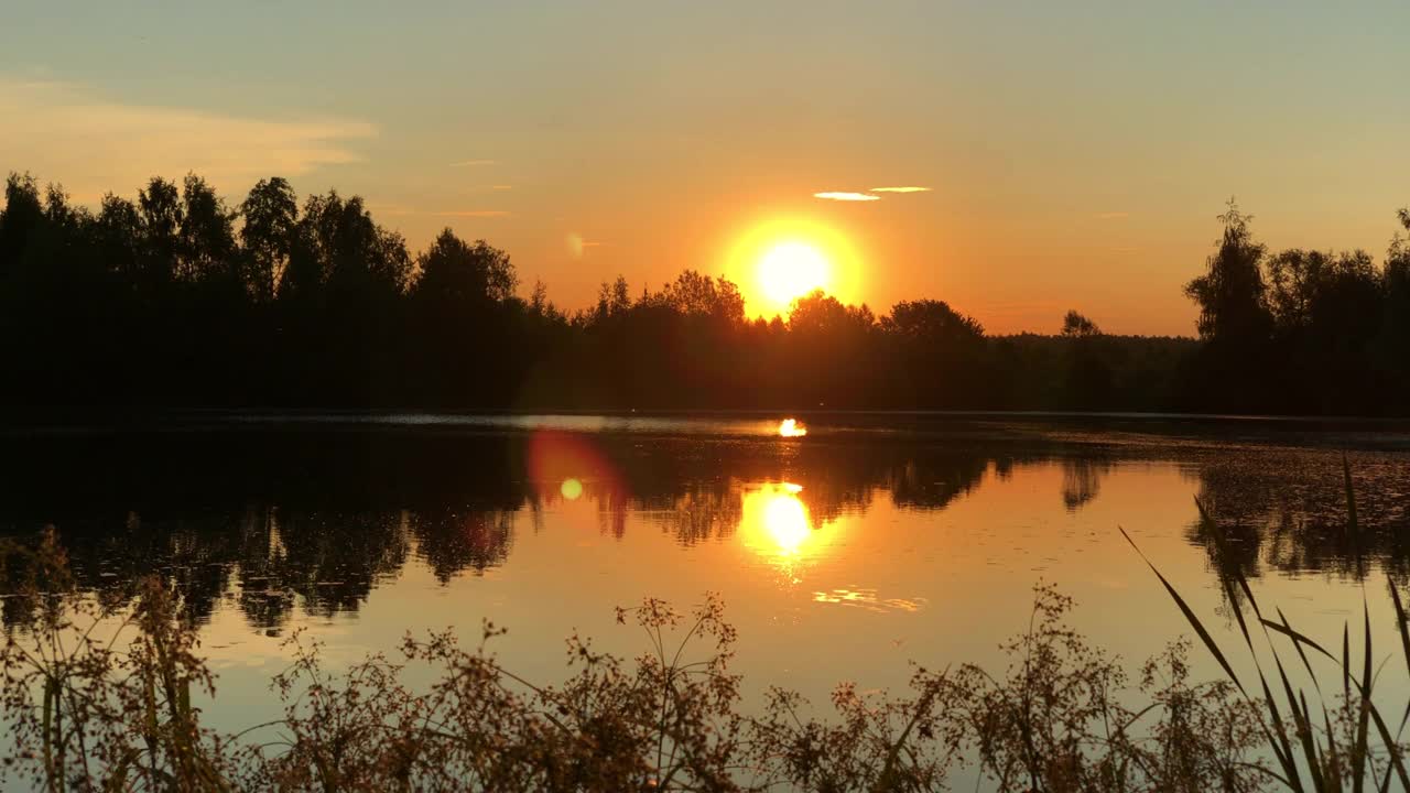 太阳落在地平线上的森林线反射在湖面上视频素材