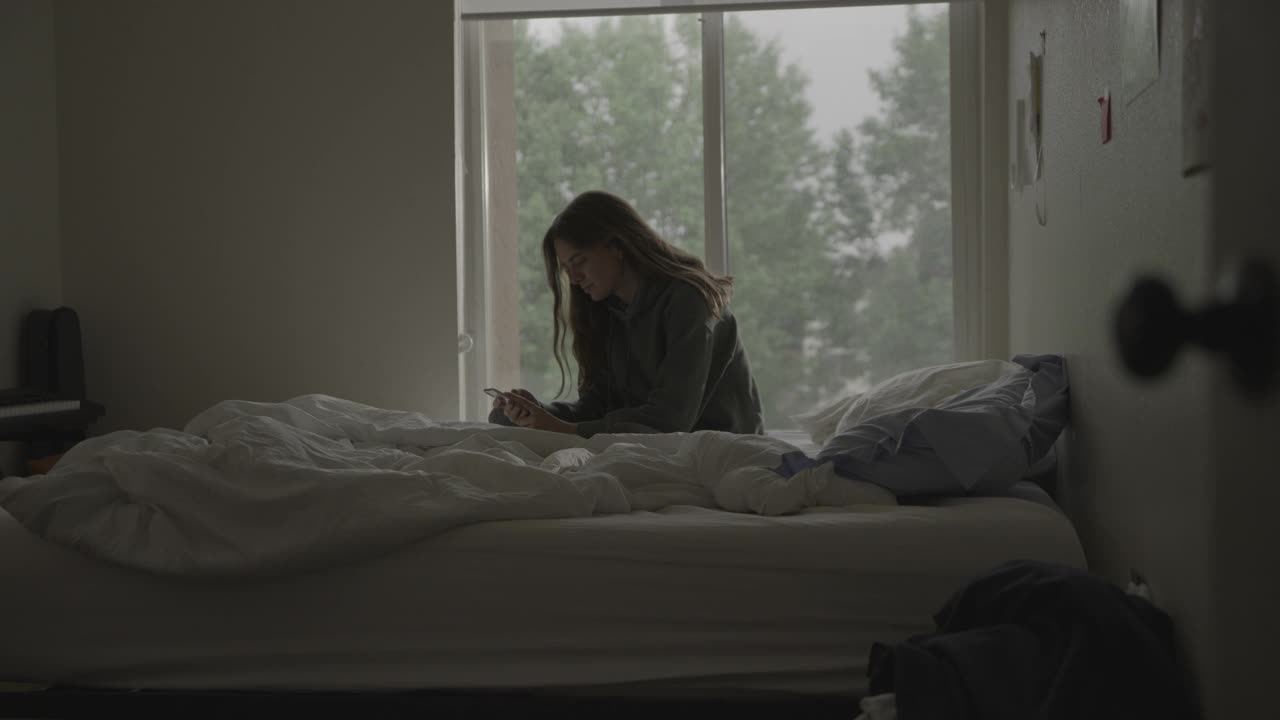 美国犹他州普罗沃，一个无聊的女人在用完手机社交媒体后躺在床上视频下载