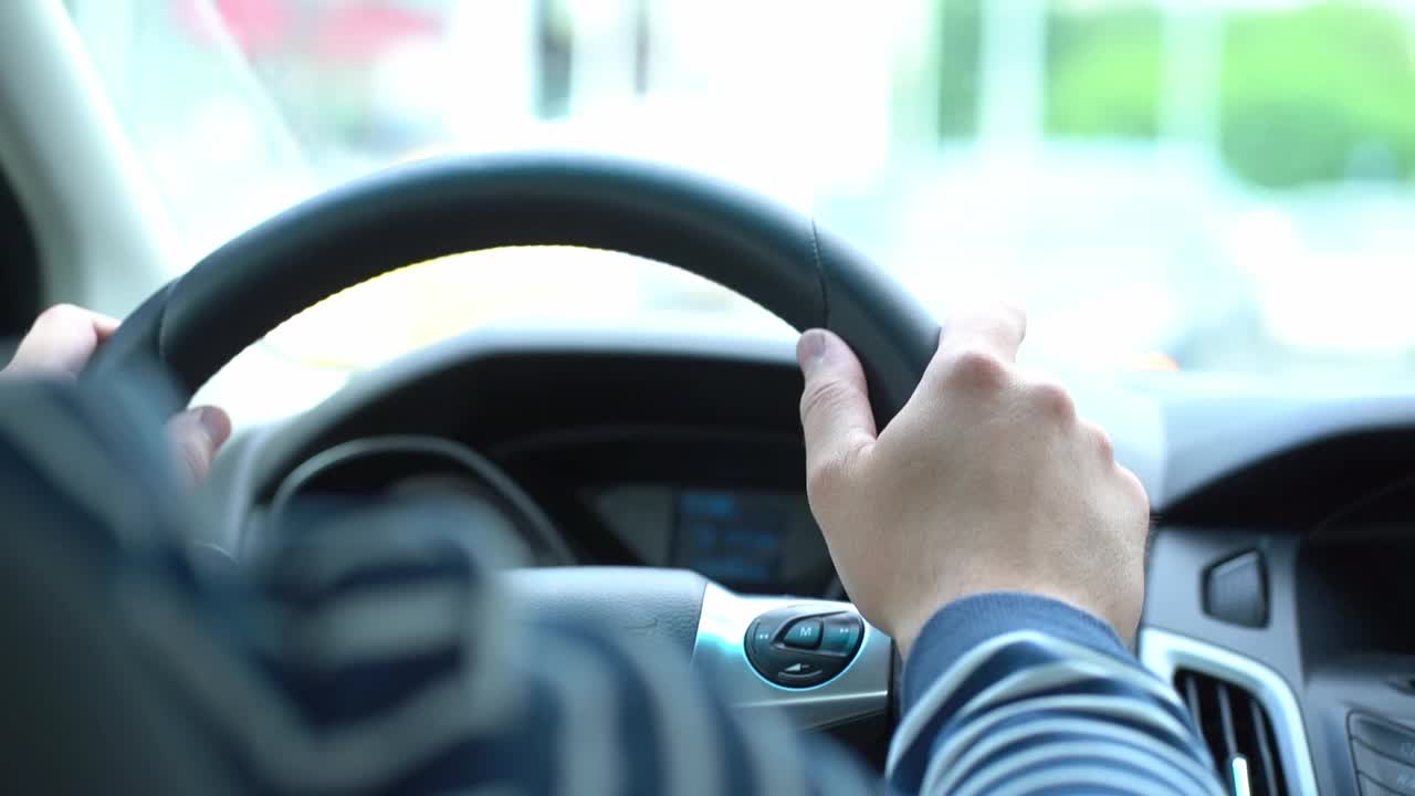 司机坐在方向盘后面，一名男子一边开车一边把手放在方向盘上，视频来自车内视频素材