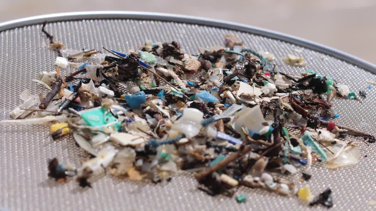 塑料污染，海水和沙子中混合的微塑料。视频下载
