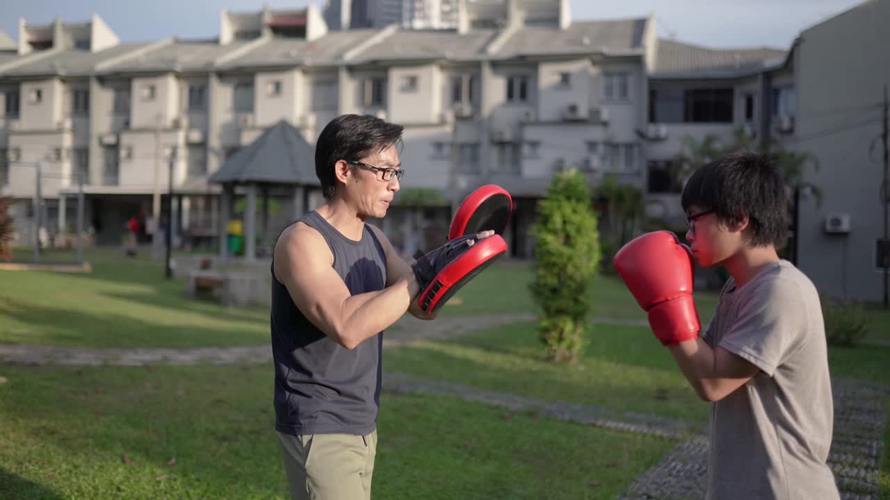 亚洲华人父亲和儿子在后院户外训练跆拳道。视频下载