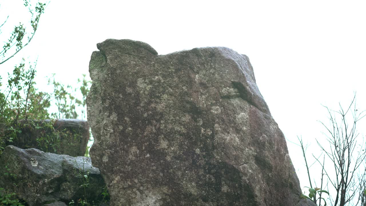 亚洲探险家、冒险家、女背包客沿着大石攀登，在恶劣天气下作为情人在热带森林徒步旅行，在泰国雨季到达顶峰，雾覆盖了整个山峰区域视频素材