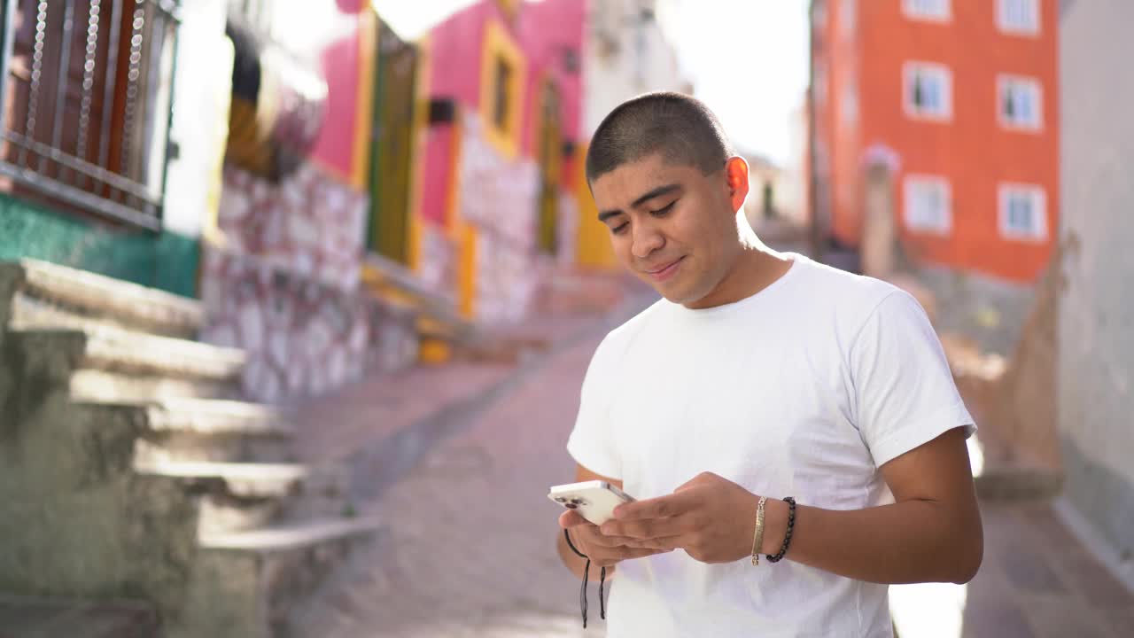 一名年轻男子在街上使用智能手机视频下载