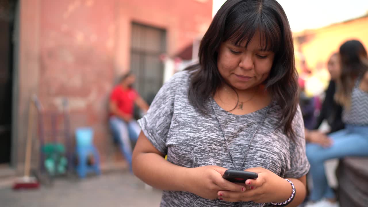 年轻女子使用智能手机走在街上视频下载