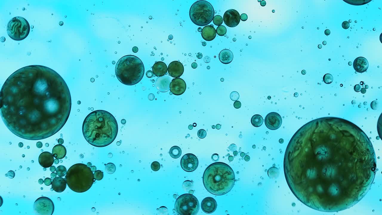 一个行星形状的液体气泡，漂浮在蓝色液体的表面。视频素材