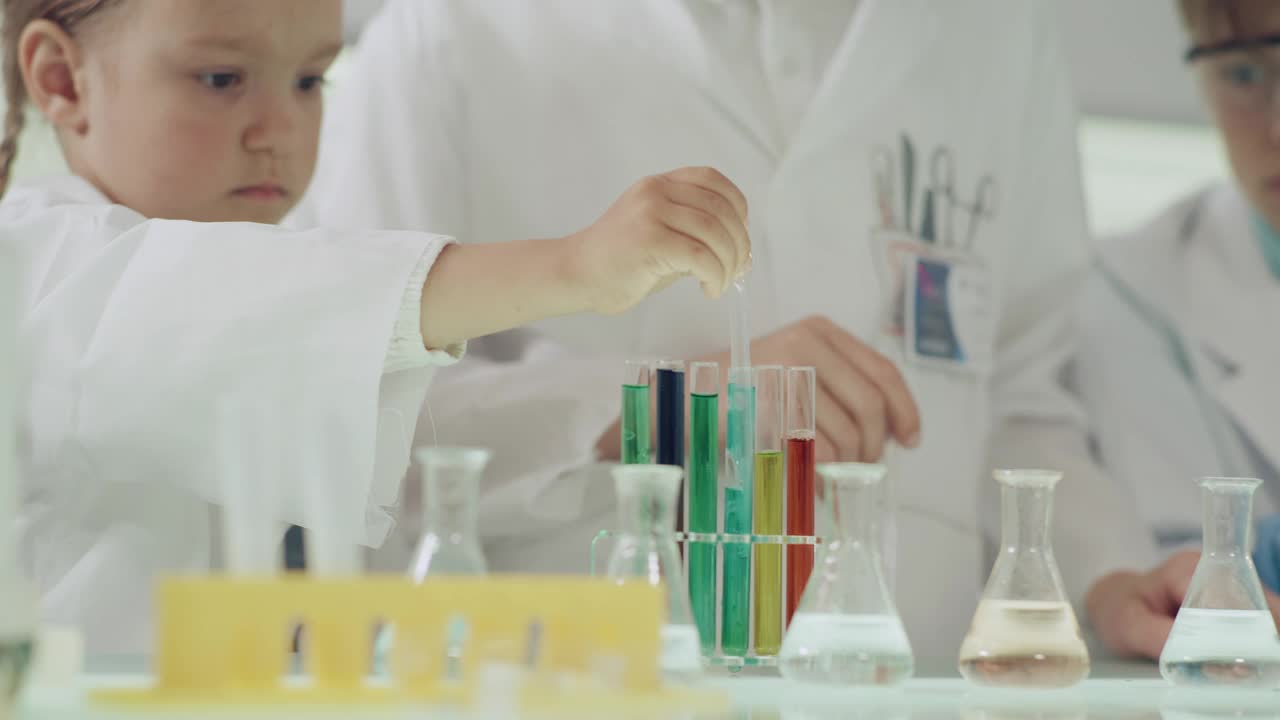 孩子们在做科学实验。实验室内部，用移液管灌注多种颜色的液体。近距离接触视频素材
