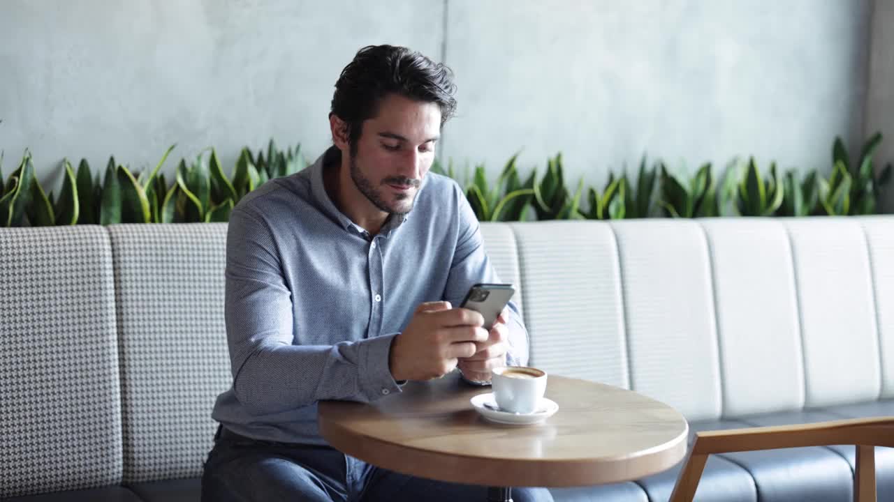 一个年轻人在咖啡馆用智能手机视频素材