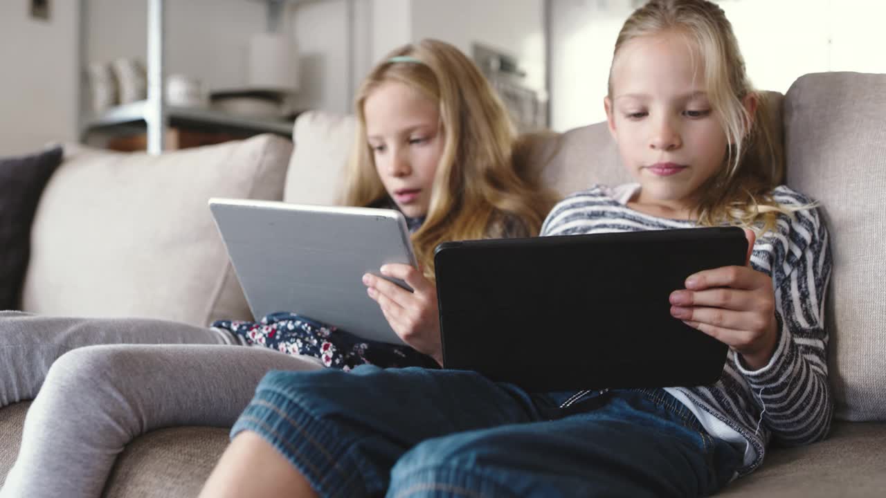 两名年轻女孩坐在家里使用数码平板电脑的4k视频片段视频下载
