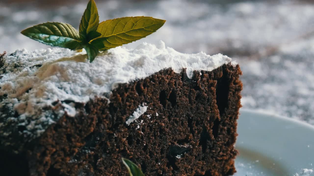 自制的巧克力布朗尼蛋糕裹上糖粉，放在装饰有薄荷叶的白盘子上。叉子从盘子里掰下一块布朗尼派视频下载