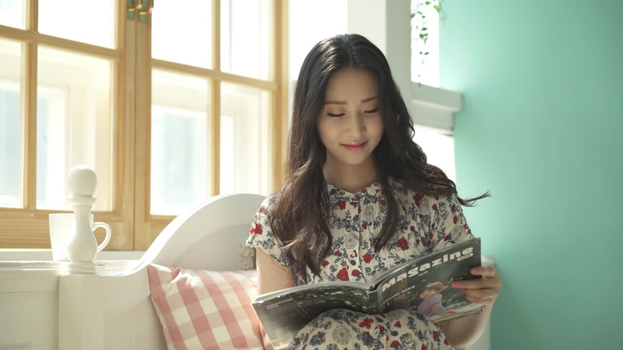 生活方式-年轻女子坐在床上阅读杂志视频素材