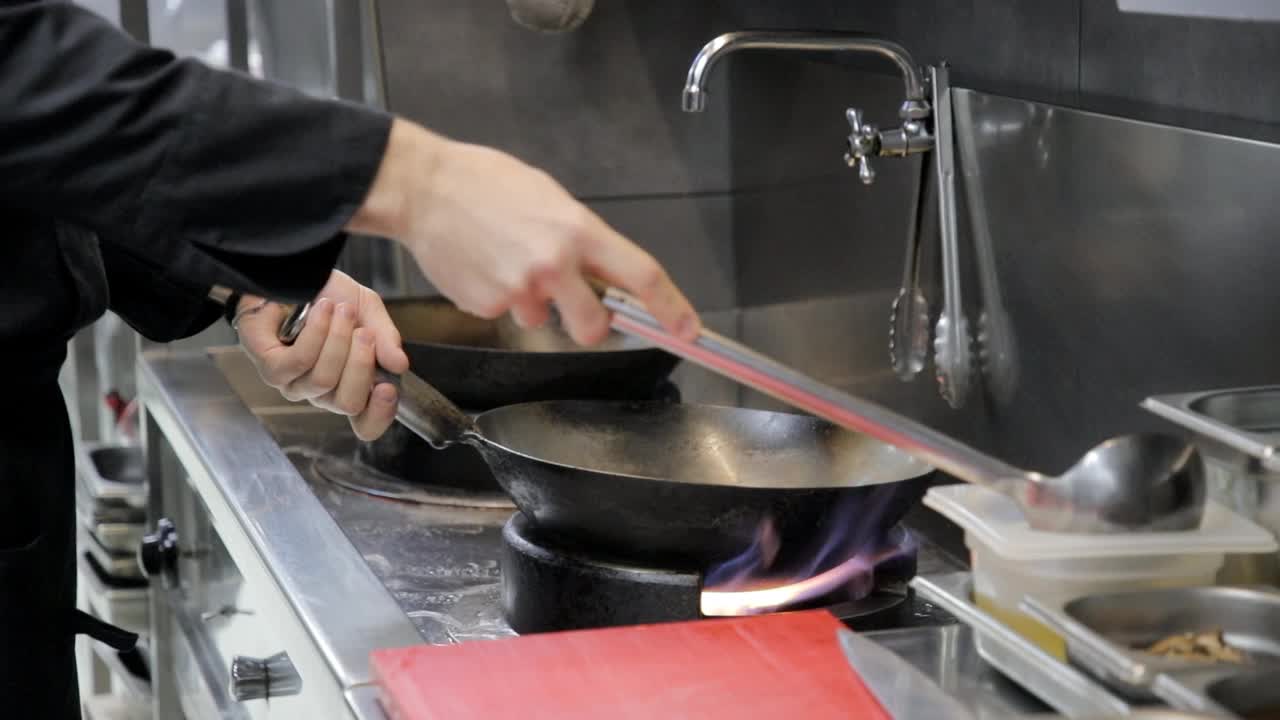 厨师用勺子将油倒入锅中，放在煤气炉上，在烹饪前将其加热视频素材