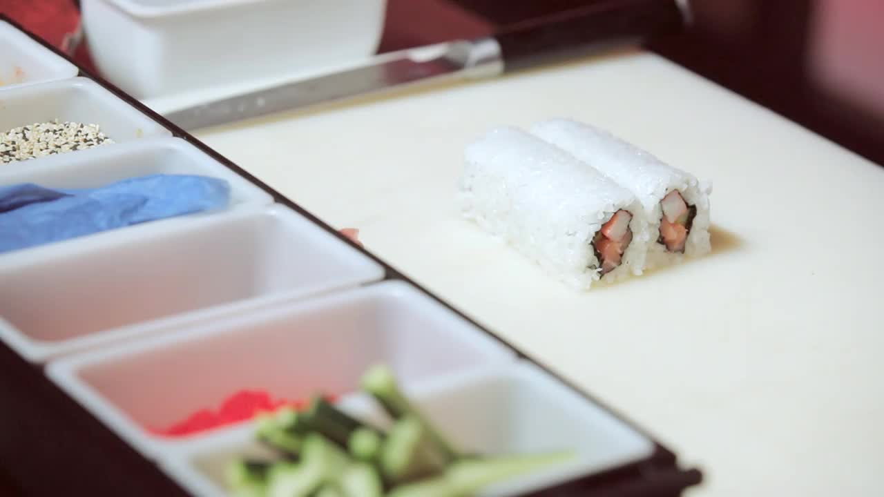 厨师的手拿着芝麻和红鱼子酱，把加州卷的米包起来视频下载