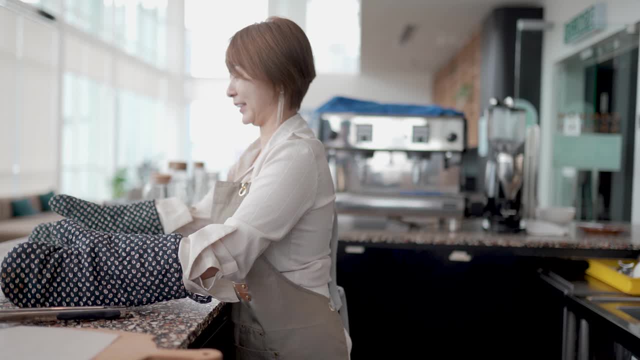 亚洲华人商人微笑着围裙端着一盘糕点送顾客视频下载