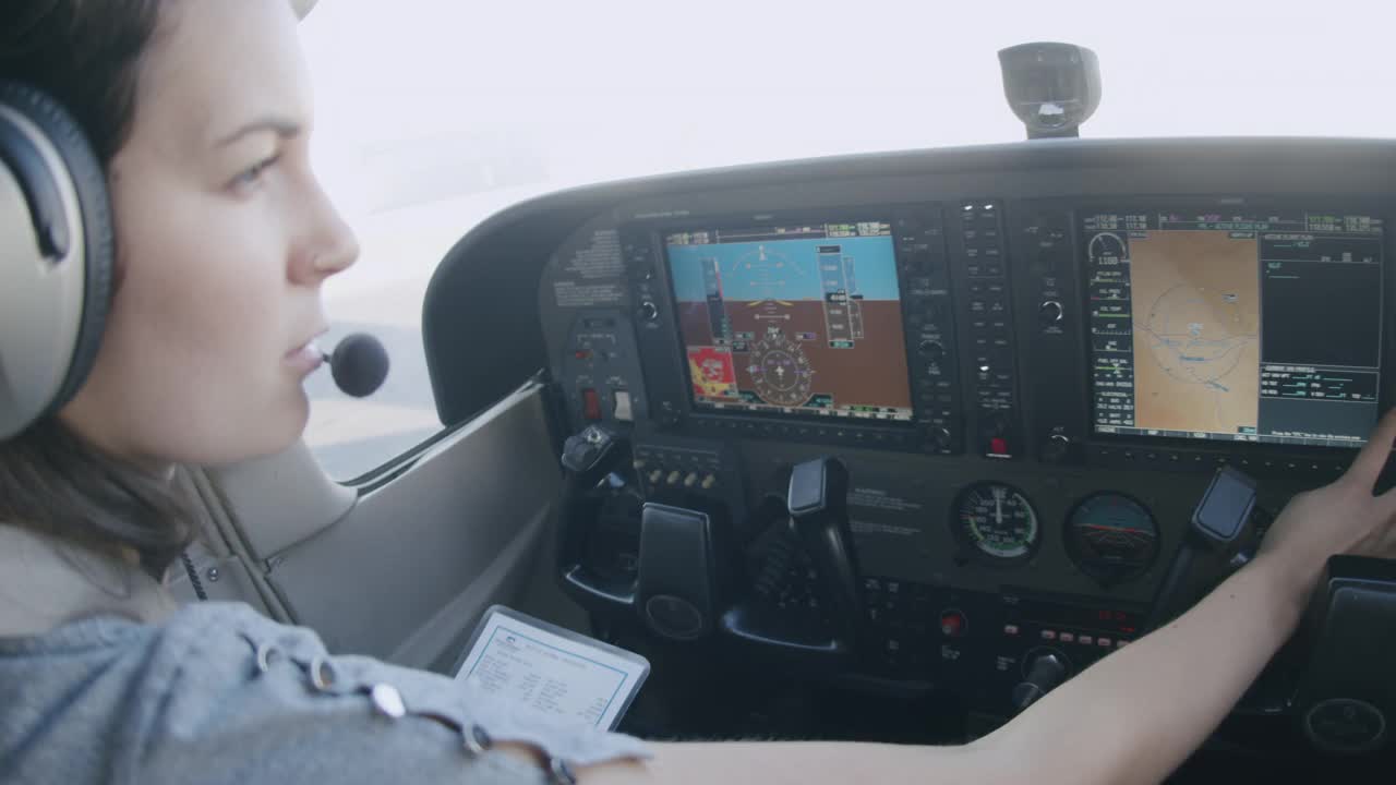 年轻成年女飞行员的手在多功能飞行控制显示器上加载飞行计划视频素材
