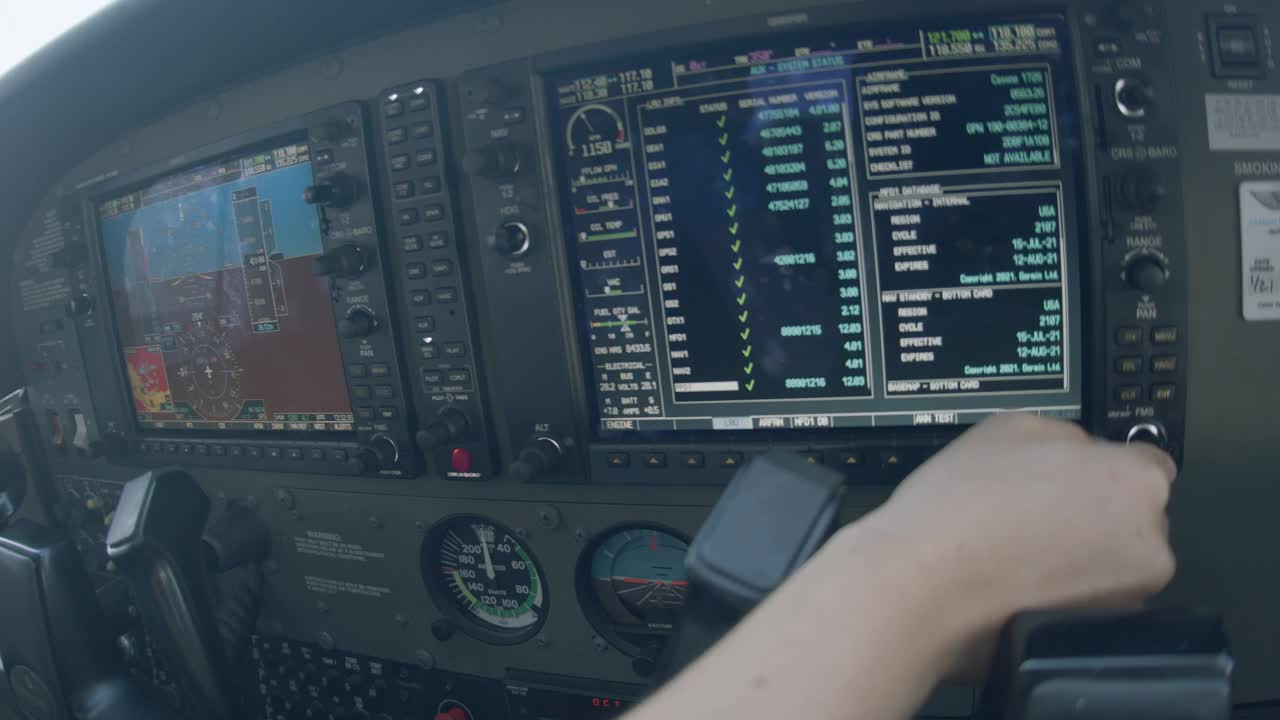 年轻的成年女飞行员的手滚动到辅助页面，检查可更换部件的线，并在多功能飞行控制显示器上运行Gps检查视频素材