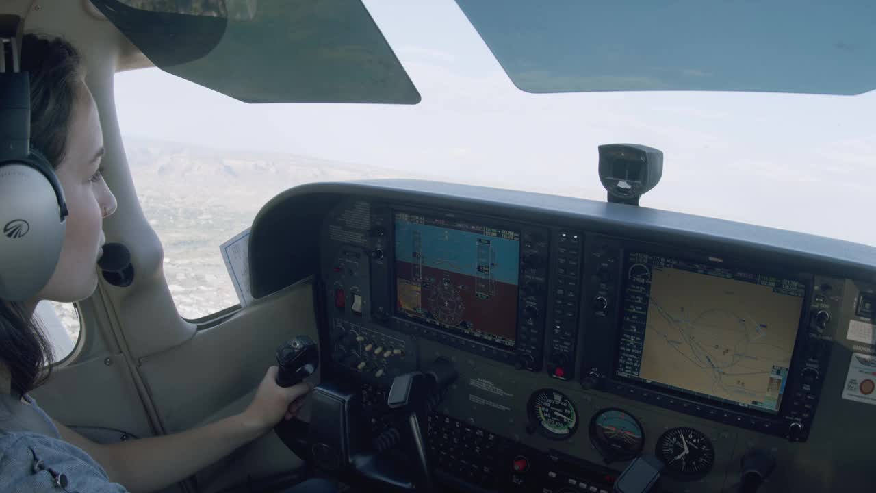 年轻的成年女性飞行员驾驶单引擎飞机，切换待机和主动无线电频率视频下载