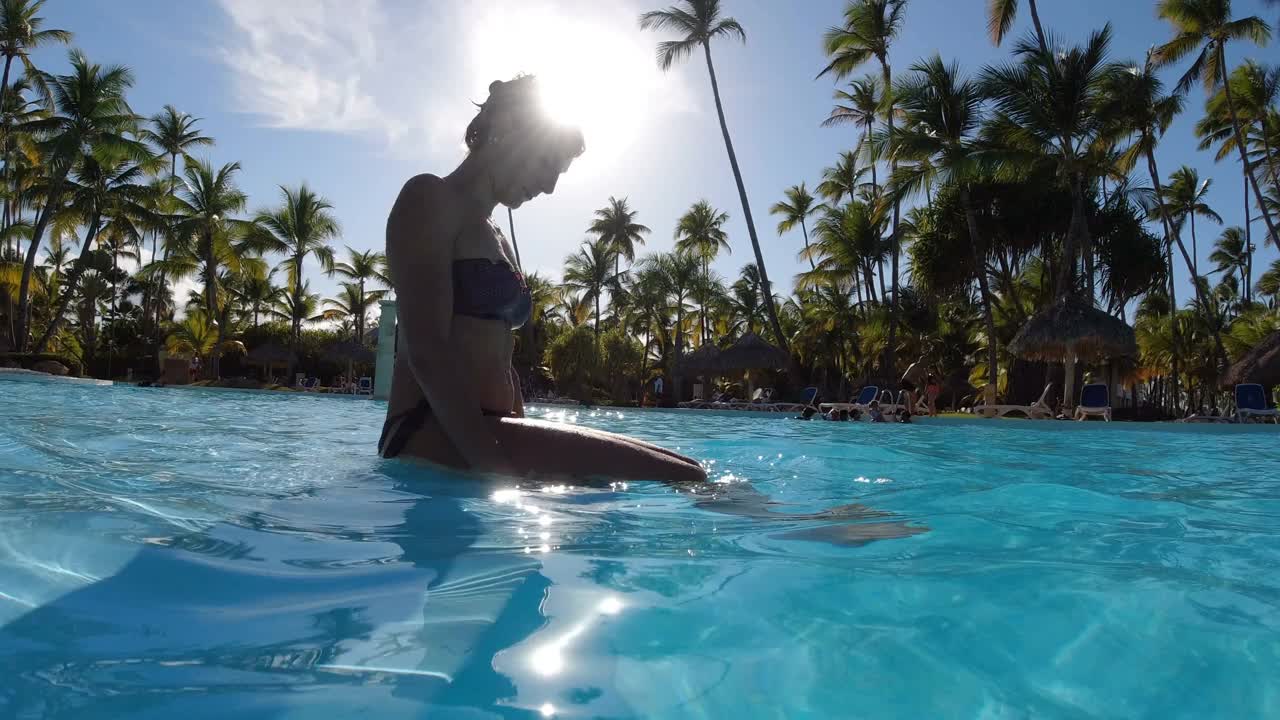 一个穿着比基尼的女人坐在泳池边视频下载