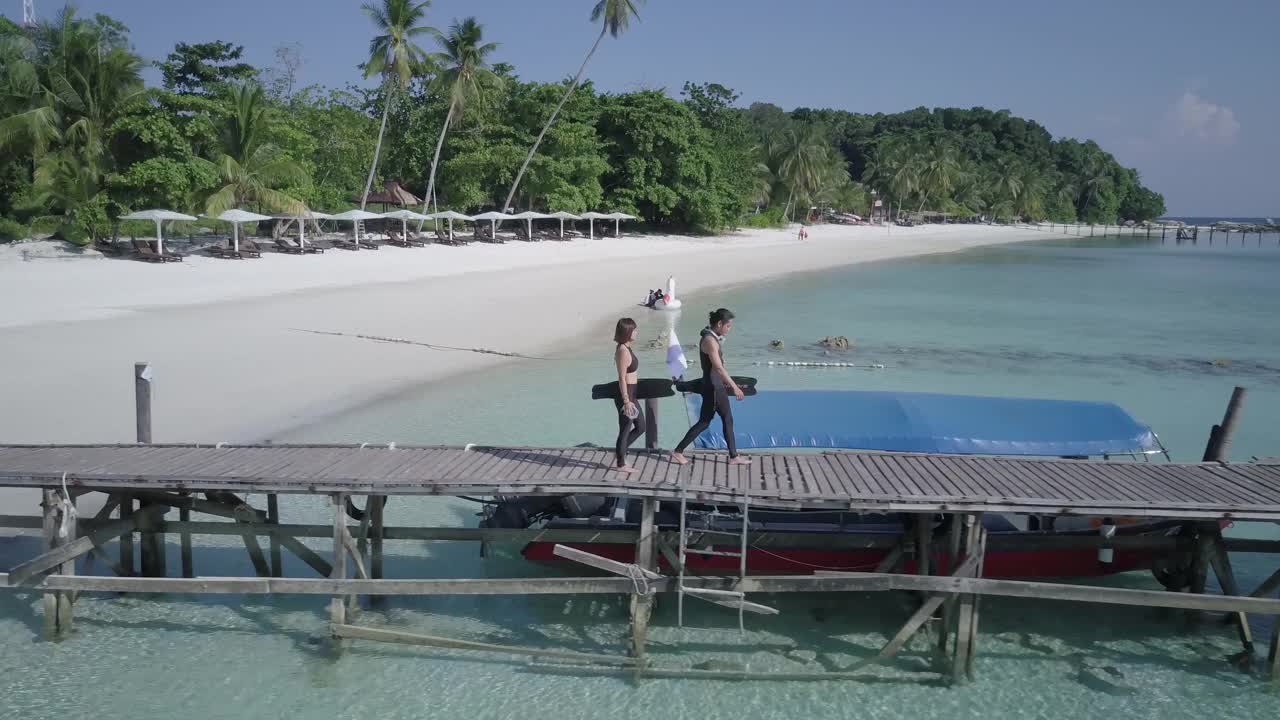 无人机拍摄的两名自由潜水员走在木制码头向大海视频下载