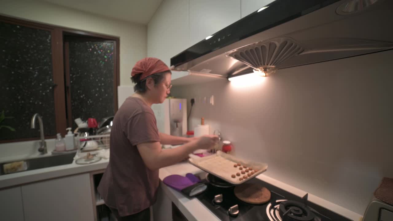 亚洲华人中年妇女在厨房拿起烤花生饼干饼干视频素材