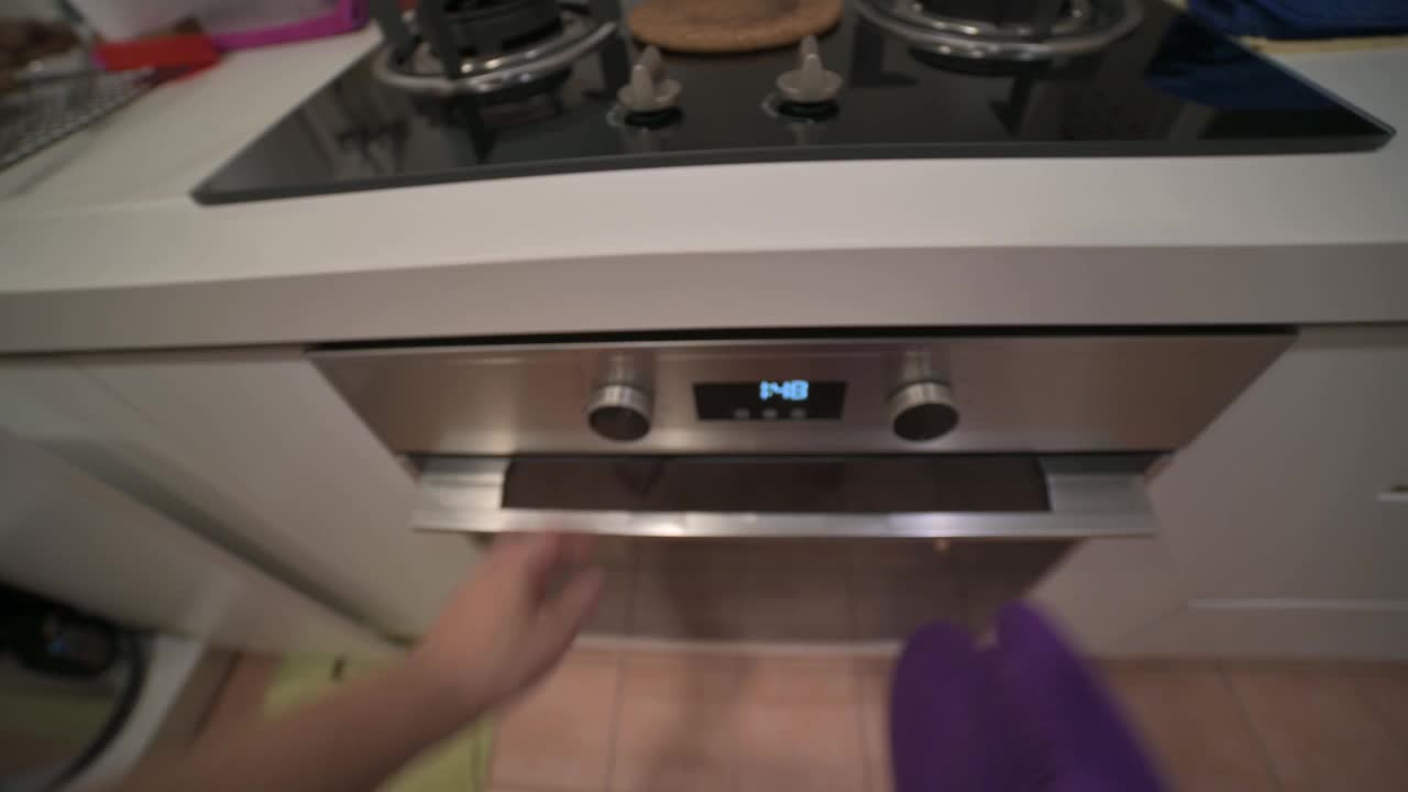 个人观点亚洲华人中年妇女在厨房用防护手套从烤箱中取出花生饼干饼干视频下载
