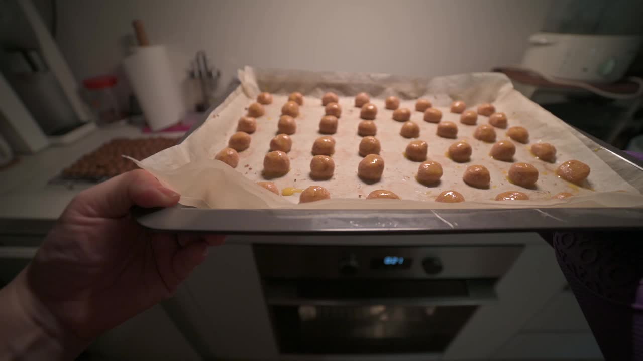 个人观点亚洲华人中年妇女在厨房用防护手套将花生饼干插入烤箱视频素材