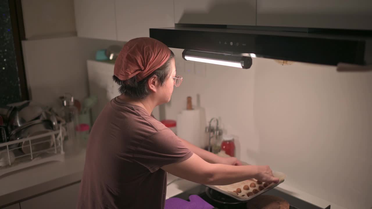 上角度看亚洲华人中年妇女在厨房拿起烤花生饼干视频素材