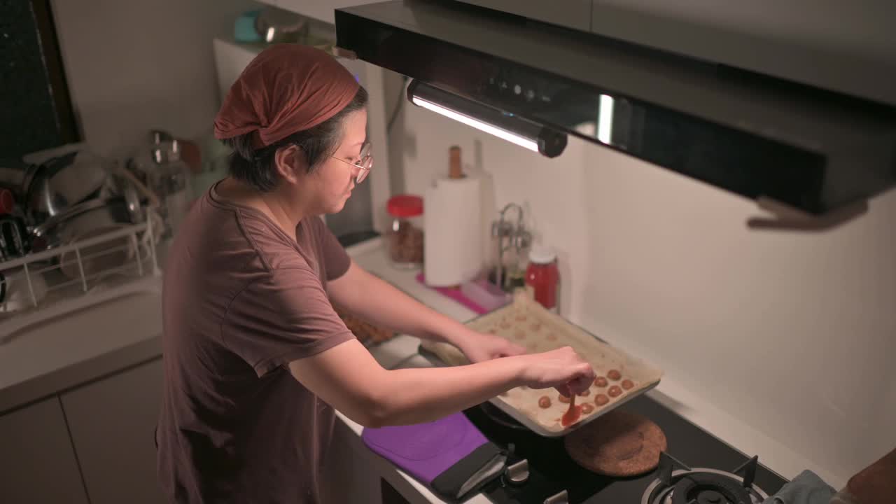 上角度看亚洲华人中年妇女在厨房拿起烤花生饼干视频下载