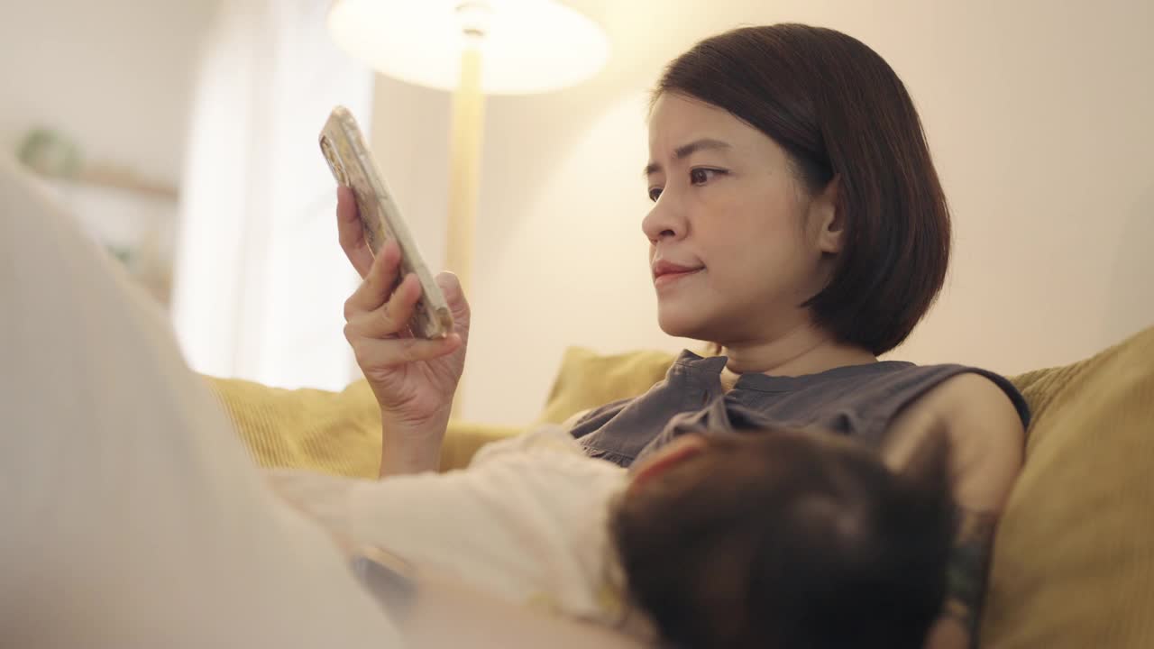 亚洲女性在客厅拿着智能手机。视频素材