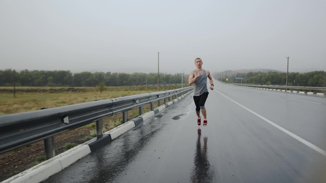 忧心忡忡的健美男子在雨中沿着公路奔跑，眼前景象。抱负和速度的概念视频素材