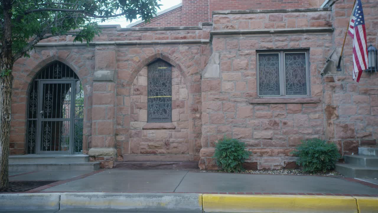 砖石建筑侧面中等角度，彩色玻璃窗和美国国旗。可能是教堂。视频素材
