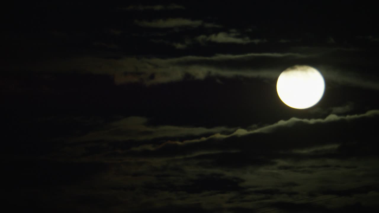 中等角度的月亮从云层之间的天空升起。视频素材