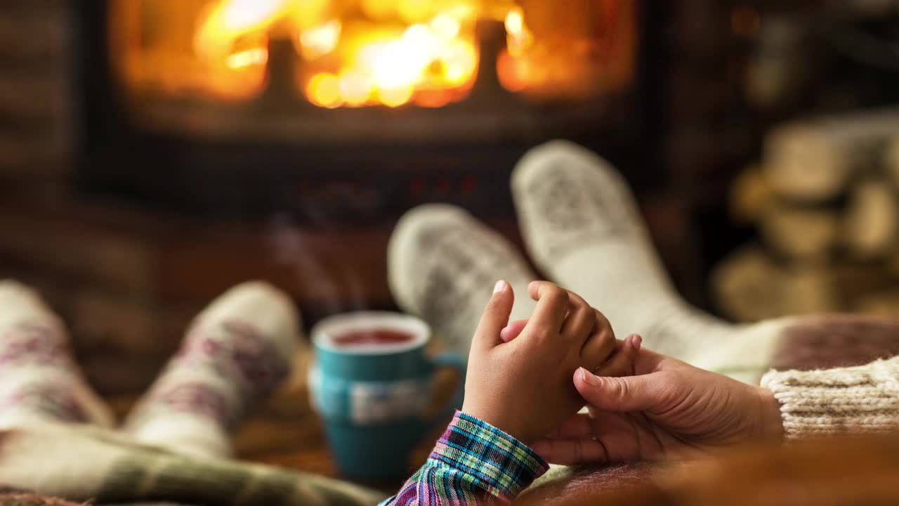 壁炉附近的温暖气氛。穿着羊毛袜子的女性和儿童的脚，热气从热饮中升起。视频下载