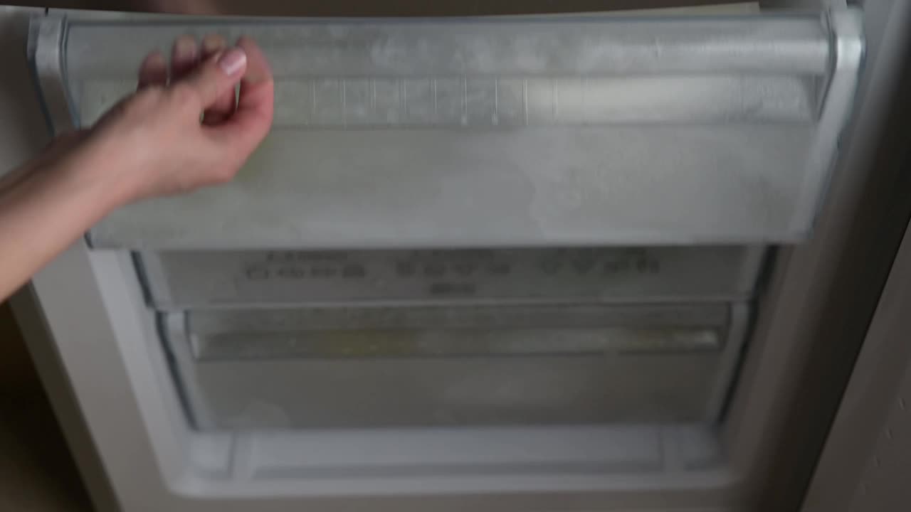 一个年轻的女人在大热天把一瓶水放在冰箱里降温视频素材