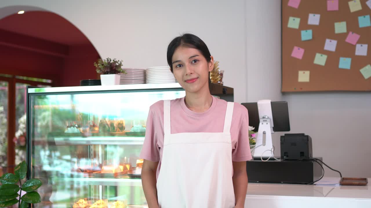 4K的亚洲女服务员肖像，交叉双臂站在吧台前。视频素材